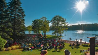 people sitting on the lawn by a lake